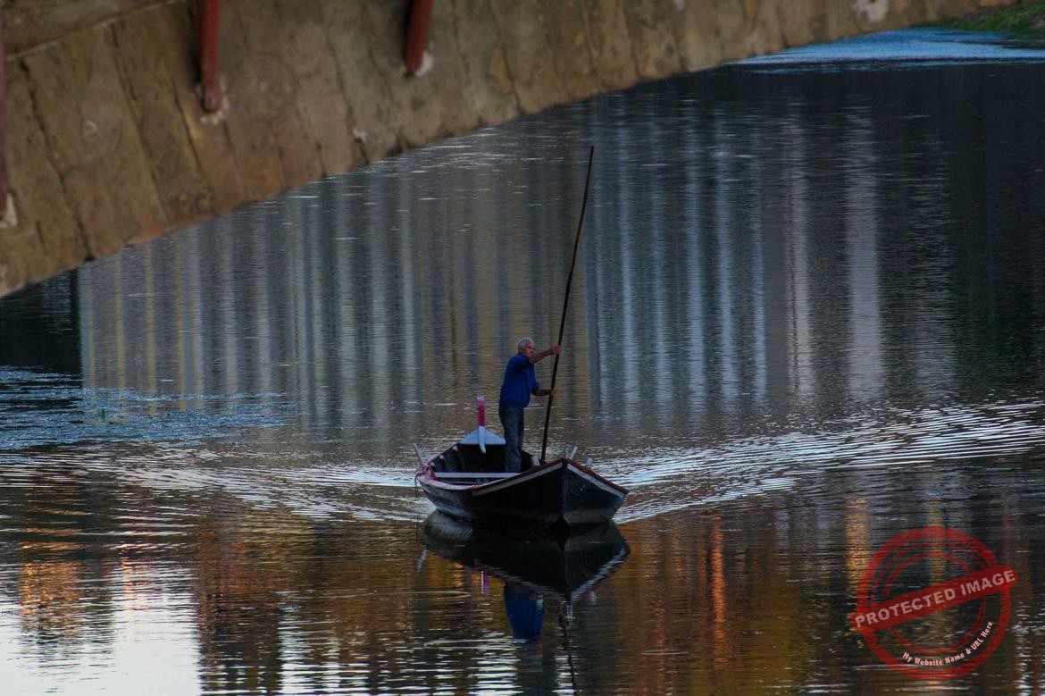 Człowiek płynący łodzią pod mostem na rzecze Arno we Florencji