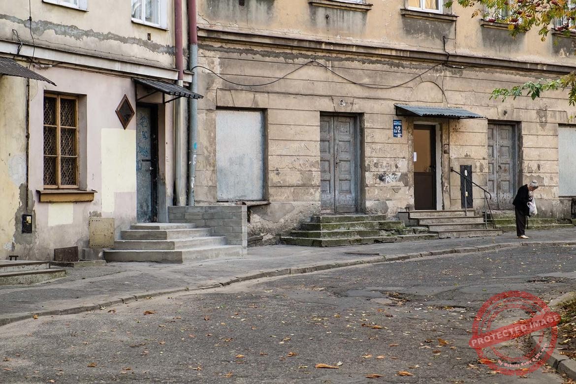 Starsza kobieta z torbą na tle budynków