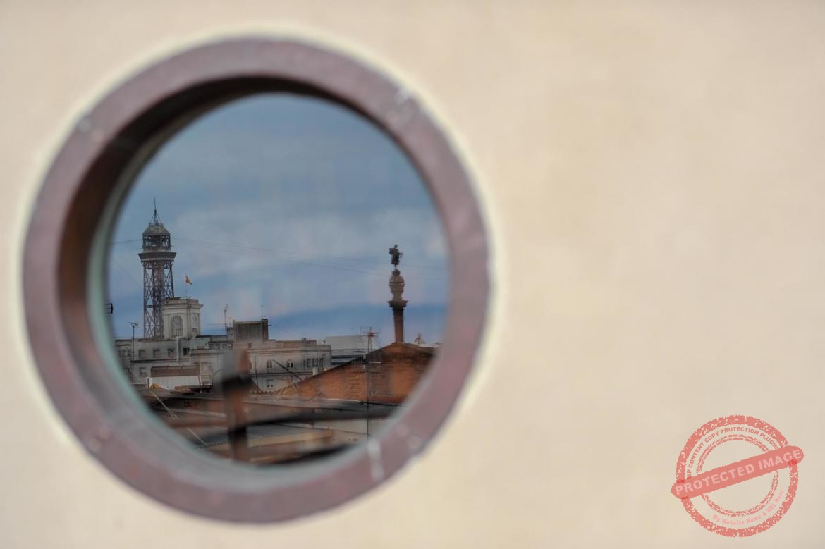 Dachy barcelony odbijające sie w oknie Pałacu Guell