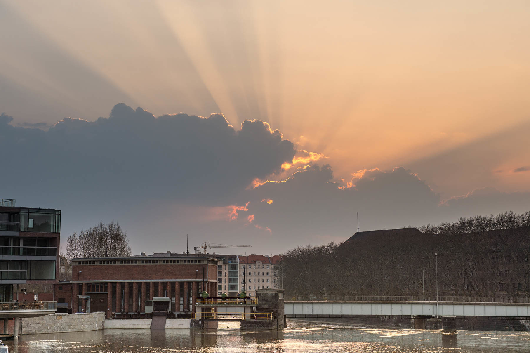 Zachodzące za chmurami słońce nad Odrą w centrum Wrocławia